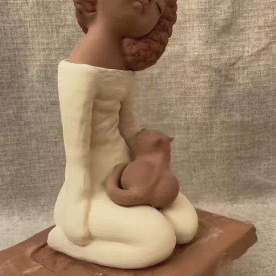 Short rotating video of a handcrafted clay woman and cat figurine, showing the sculpture from all angles and revealing handmade details and natural ceramic texture